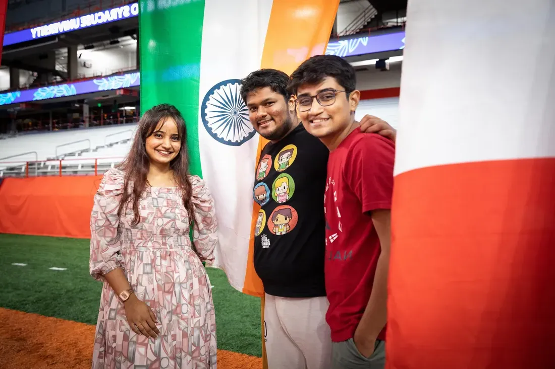 Three people standing in front of flags.